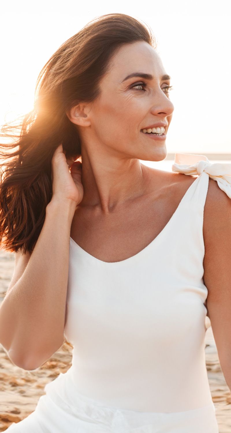 med spa patient model smiling on beach at sunset.