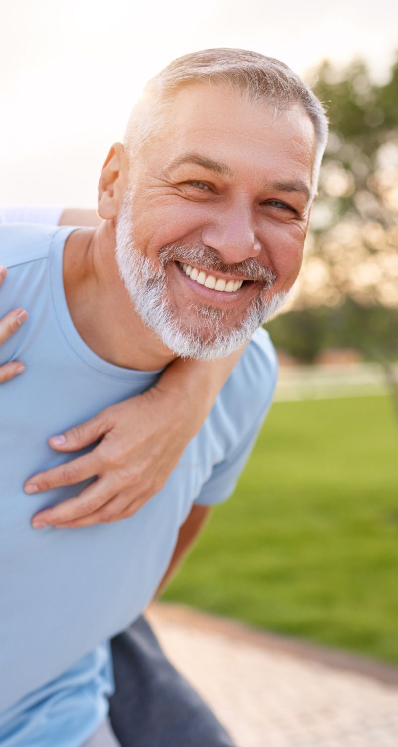 Smiling man with a playful embrace outdoors.