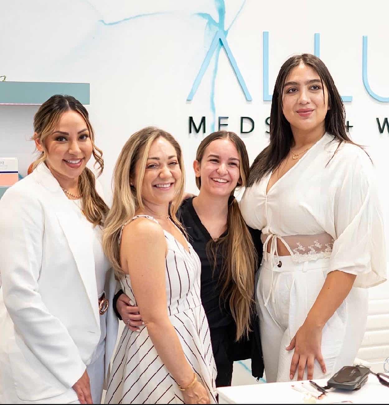 Group of four women smiling together indoors.