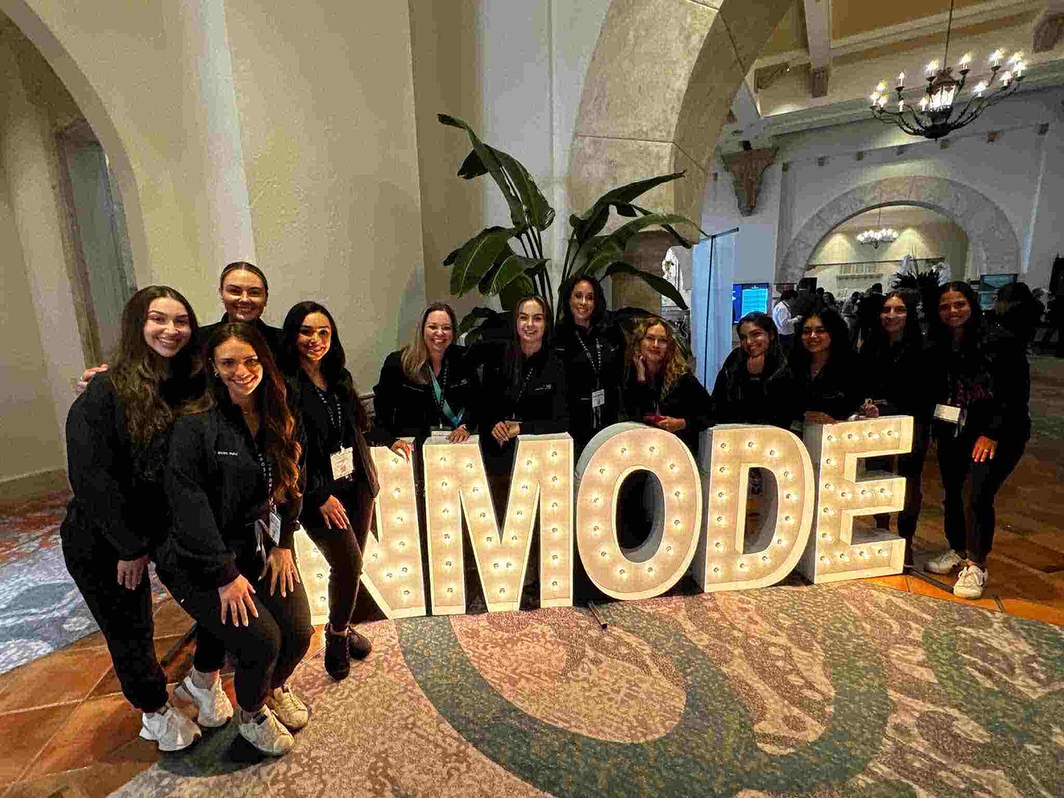 Group photo at IMODE event with glowing letters.