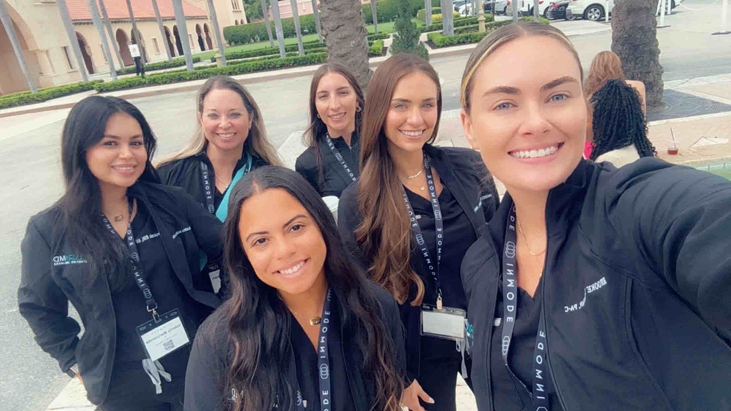 Group of professionals posing for a selfie outdoors.