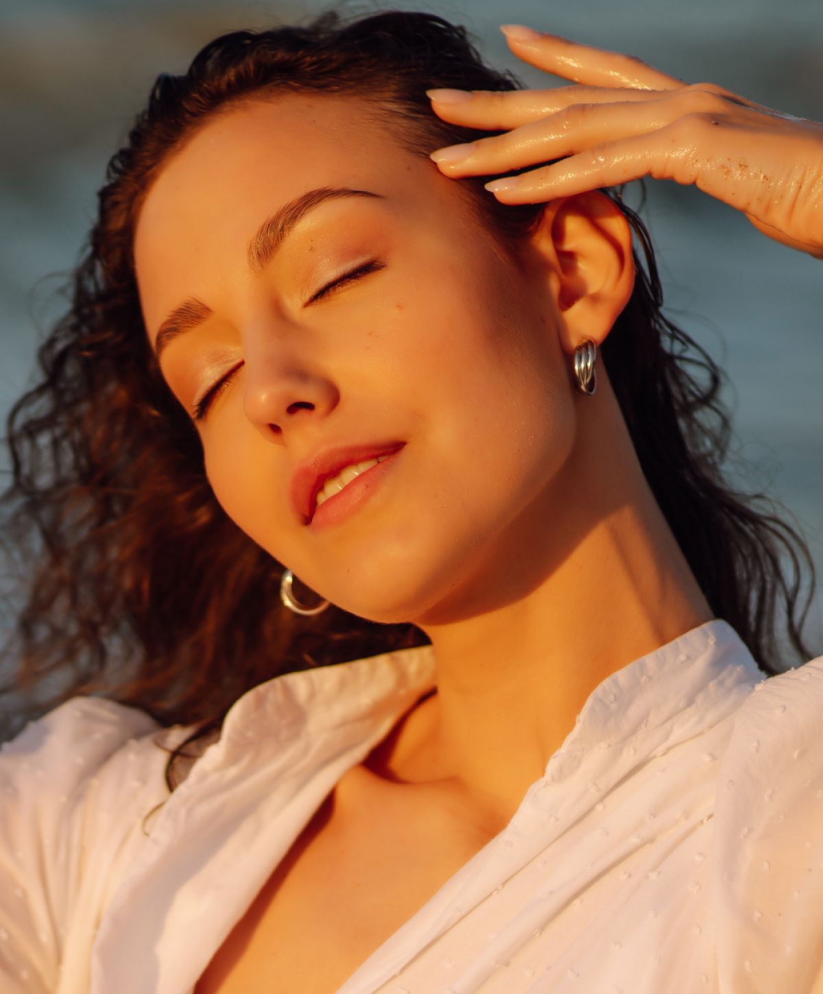 Woman with curly hair enjoying warm sunlight.