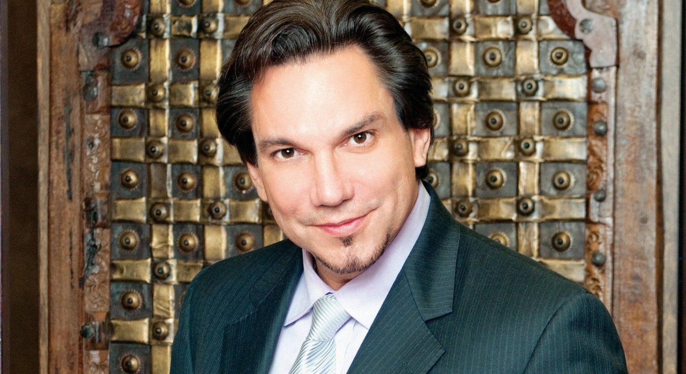 Man in suit smiling against textured background.