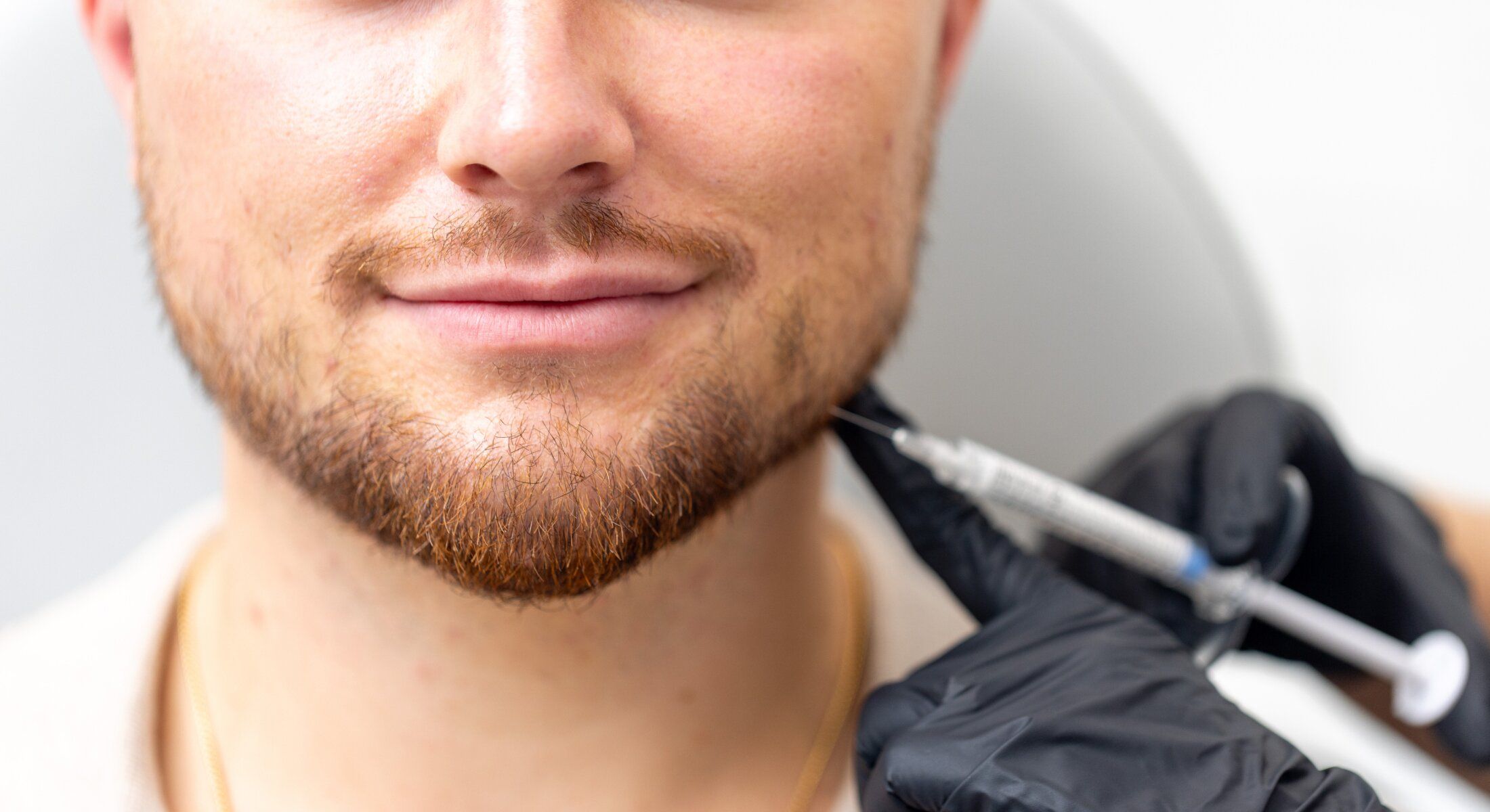 Man receiving facial treatment with syringe.