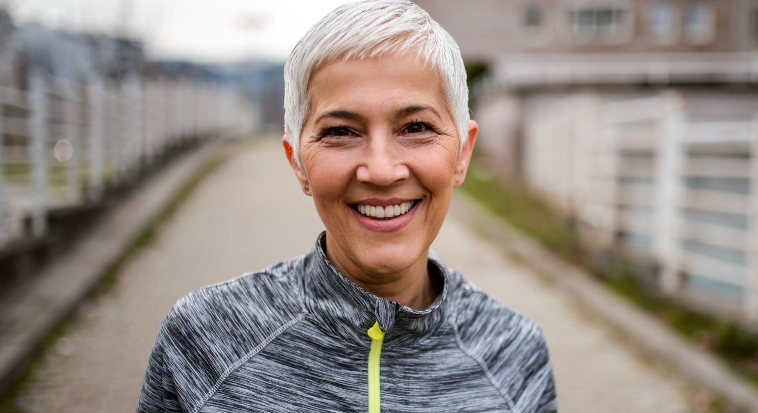 Stem Cell Therapy patient model in a gray jumper smiling on a walking path