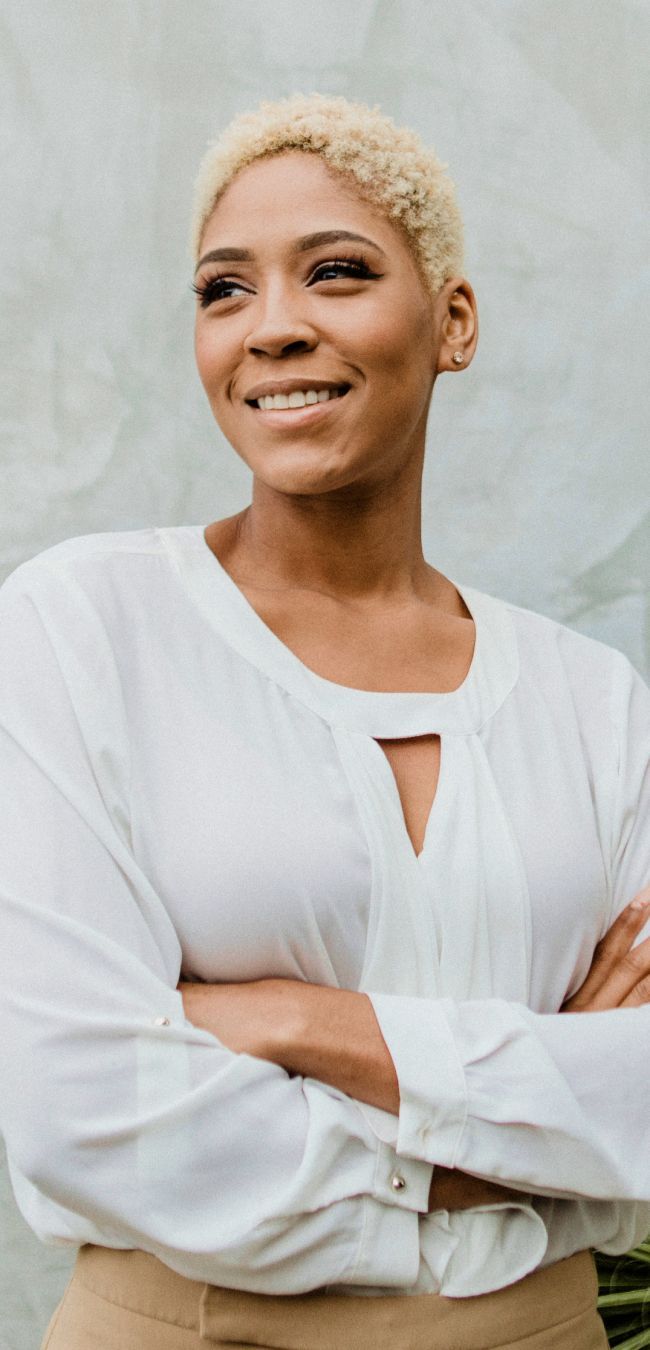 Smiling woman in white blouse against textured background.