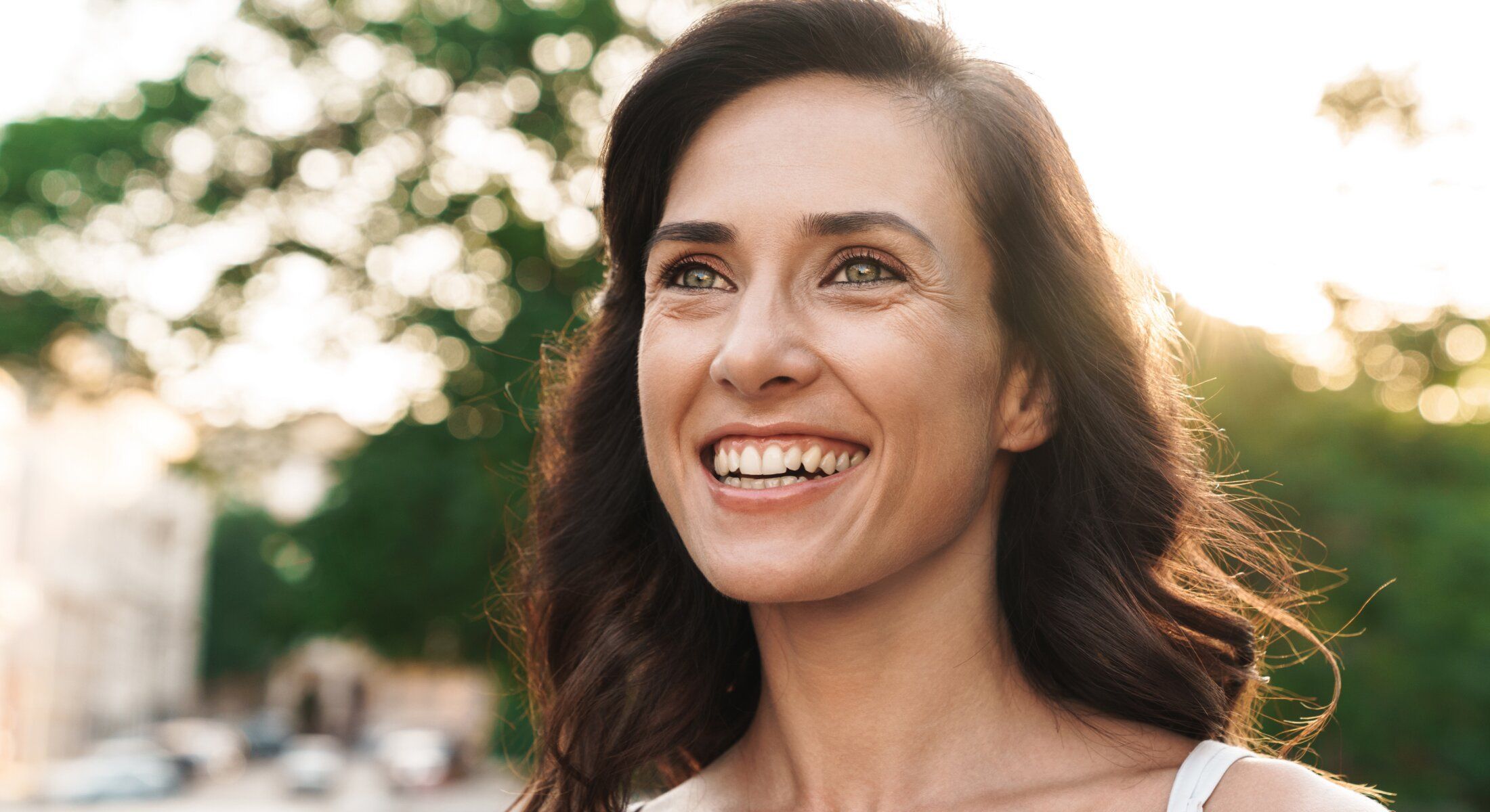 Smiling woman with sunlight in soft background.