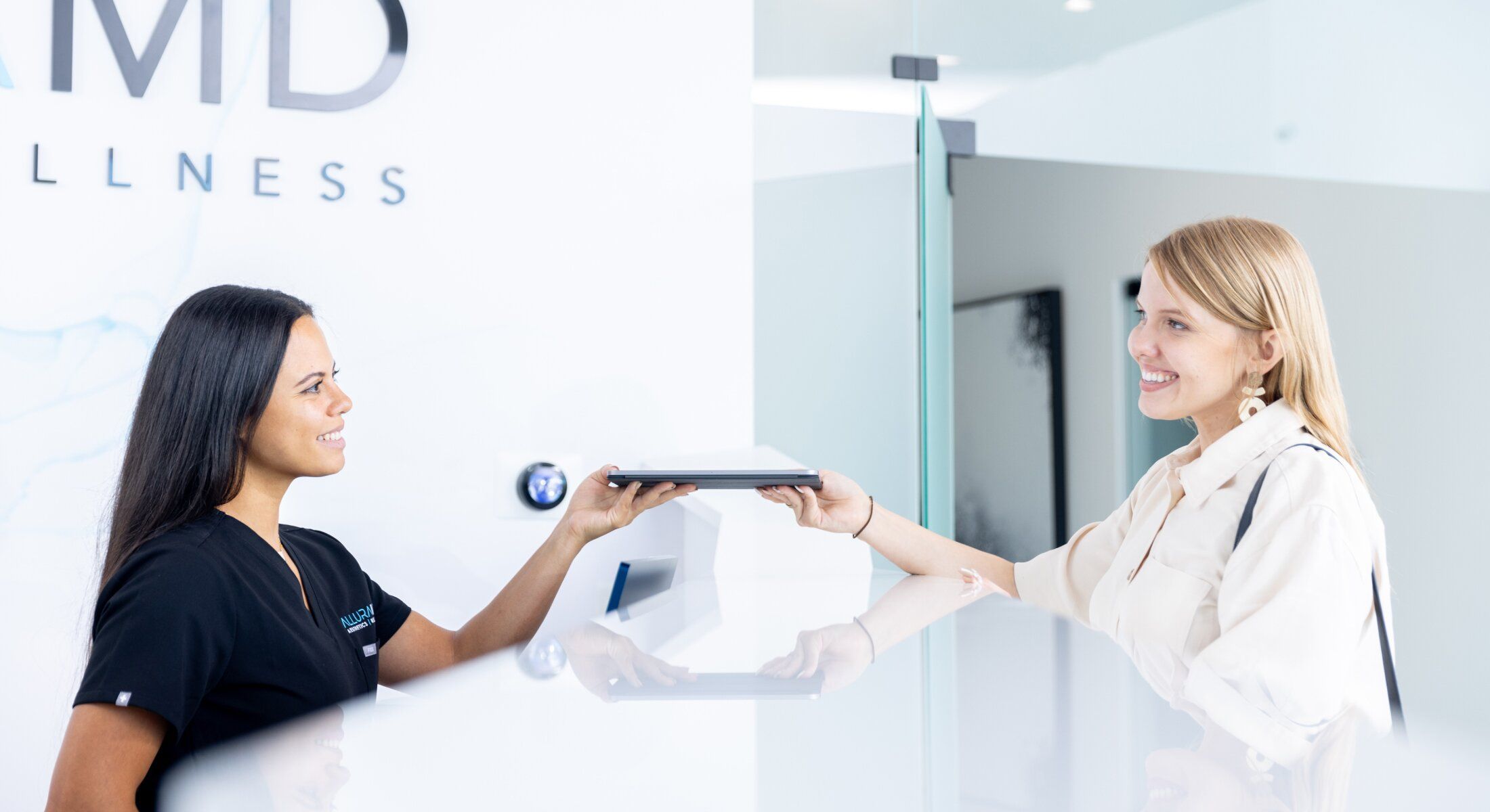 Receptionist handing tablet to a smiling client.